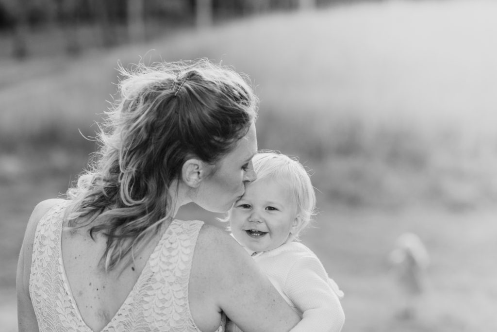 mom kissing baby in black and white